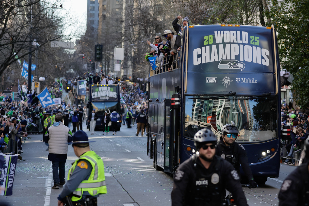 Blue double-decker parade bus with 'World Champions' sign, fans cheering on sidewalks and police in foreground.