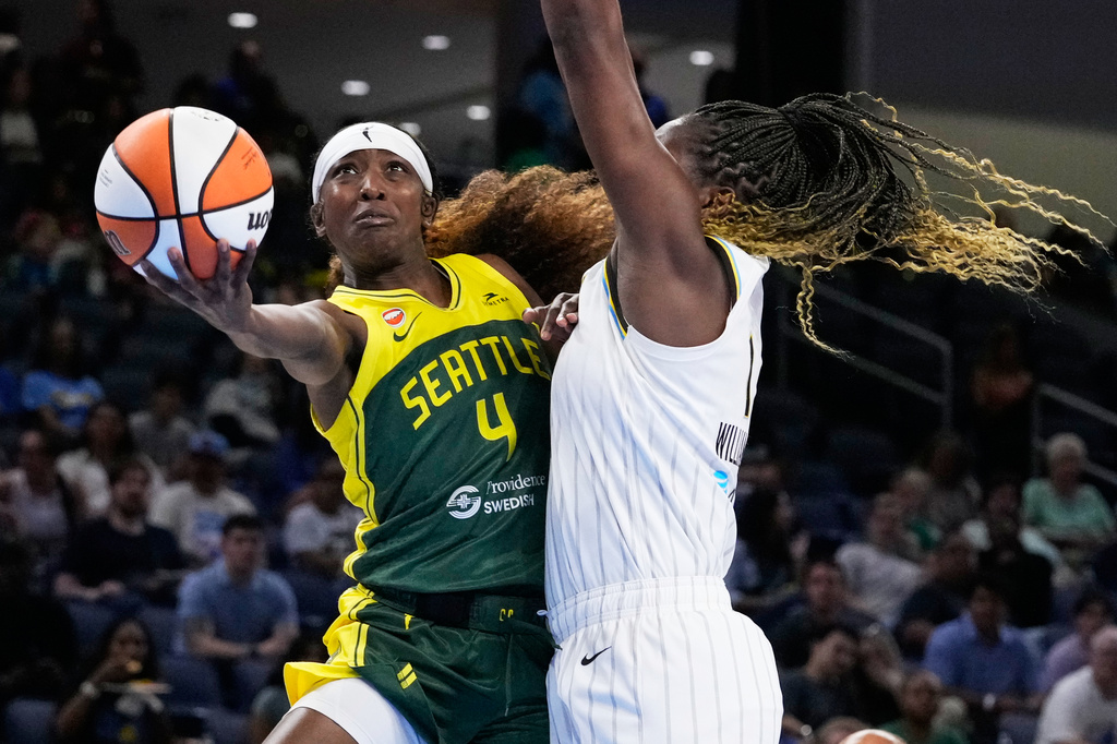 Seattle Storm player (#4) in yellow-green uniform drives with the ball as a defender in white reaches in near the hoop area?