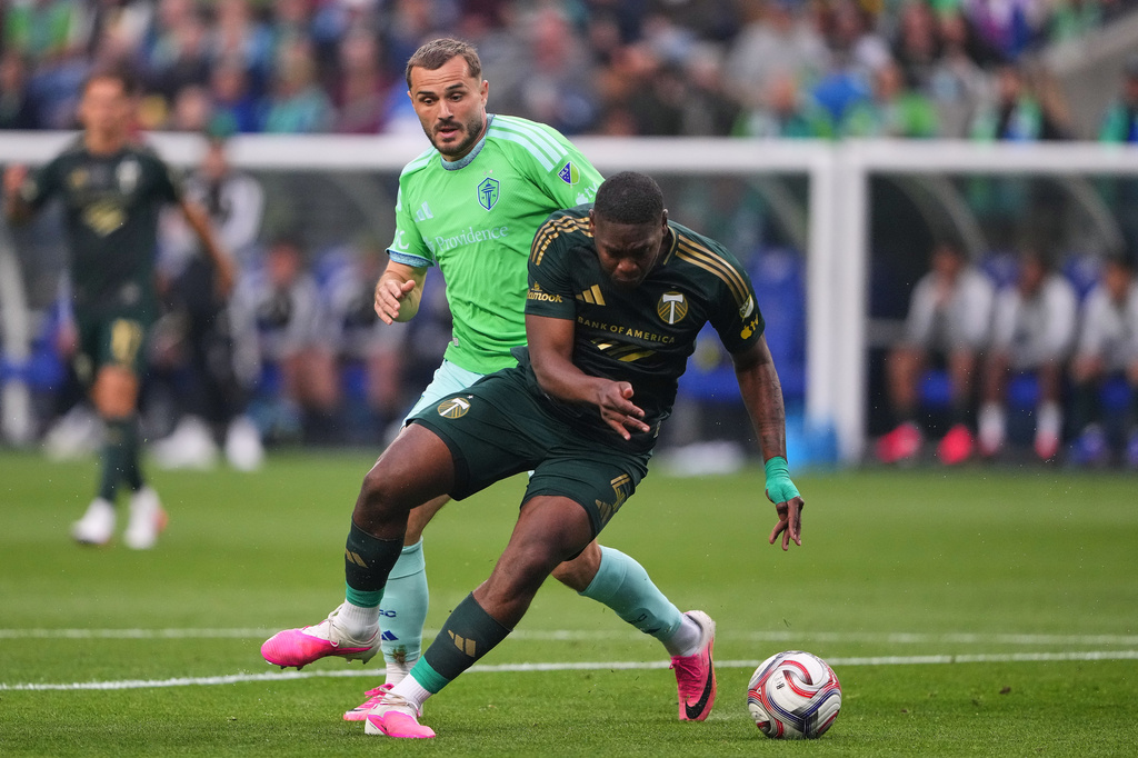 Two soccer players battle for the ball during a match on a green field, with one in a bright green jersey and the other in dark kit close in pursuit.