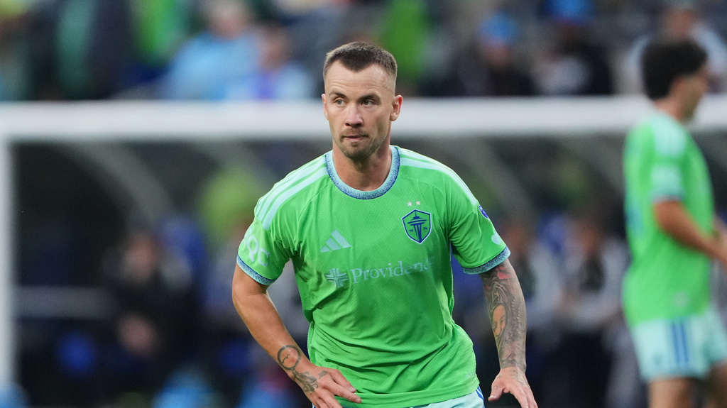 Soccer player in bright green jersey standing on the field, looking focused during a match.