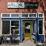 Front of Avellino Coffeehouse with blue storefront trim, yellow door, and outdoor metal tables and chairs under a tree-shadowed wall.