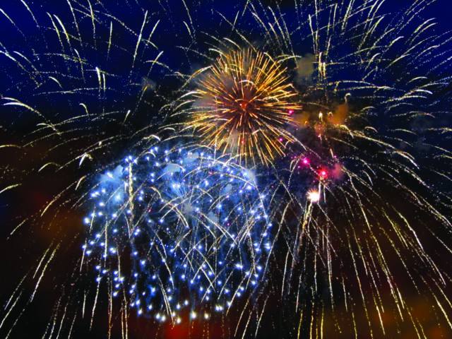Fireworks bursting in a dark blue night sky with golden streaks and blue sparks radiating outward.
