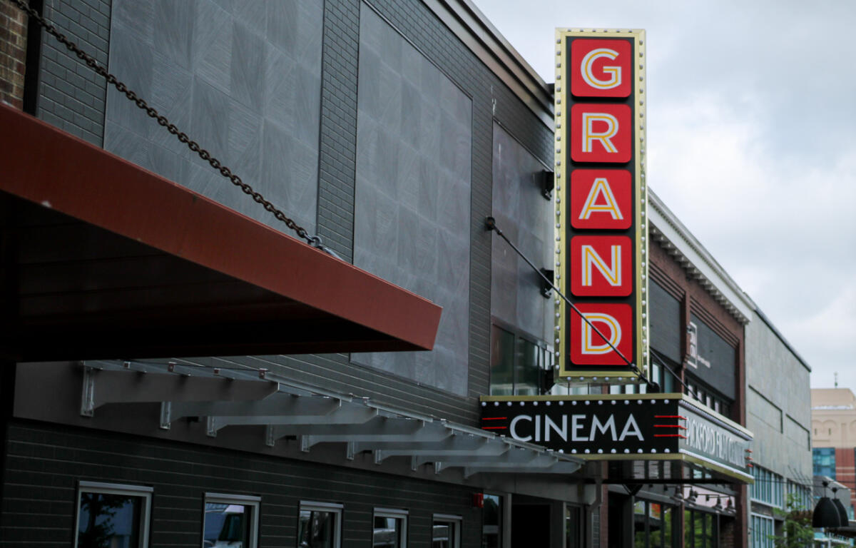 Vertical GRAND sign on a cinema façade beside a black marquee that reads CINEMA.