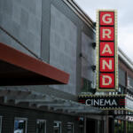Vertical GRAND sign on a cinema façade beside a black marquee that reads CINEMA.