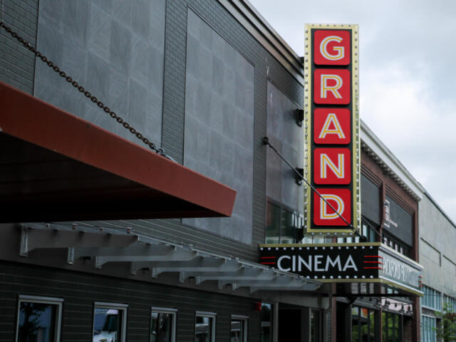 Vertical GRAND sign on a cinema façade beside a black marquee that reads CINEMA.