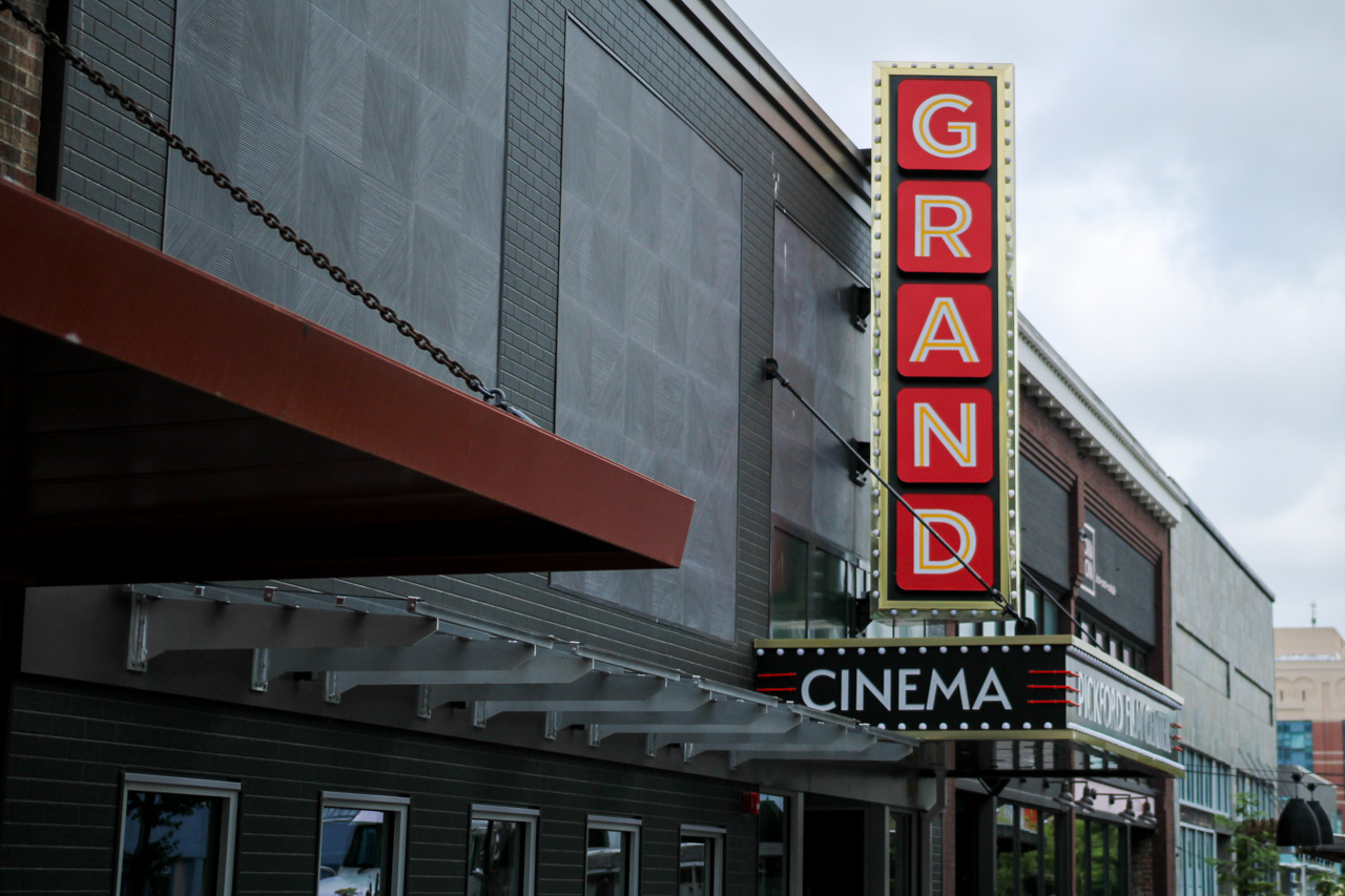 Vertical GRAND sign on a cinema façade beside a black marquee that reads CINEMA.