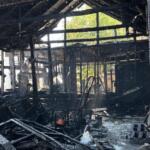 Charred interior of a burned building with blackened beams, scattered debris, and lingering smoke