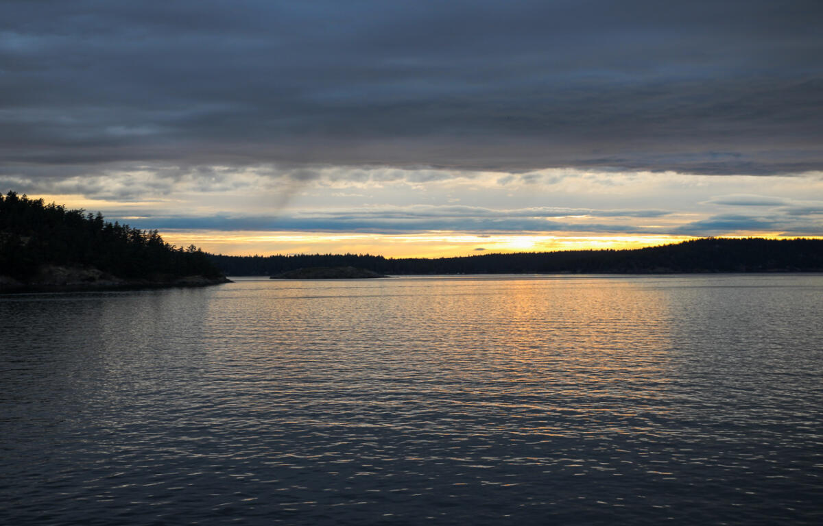 The Salish Sea with San Juan Islands in the west. Heavy storm clouds are overhead.