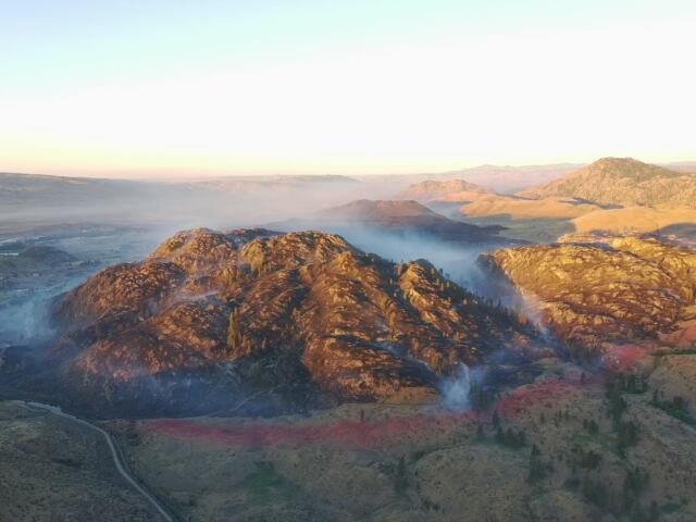 Mountain ridge at sunrise with soft fog filling the valleys and distant hills bathed in warm light