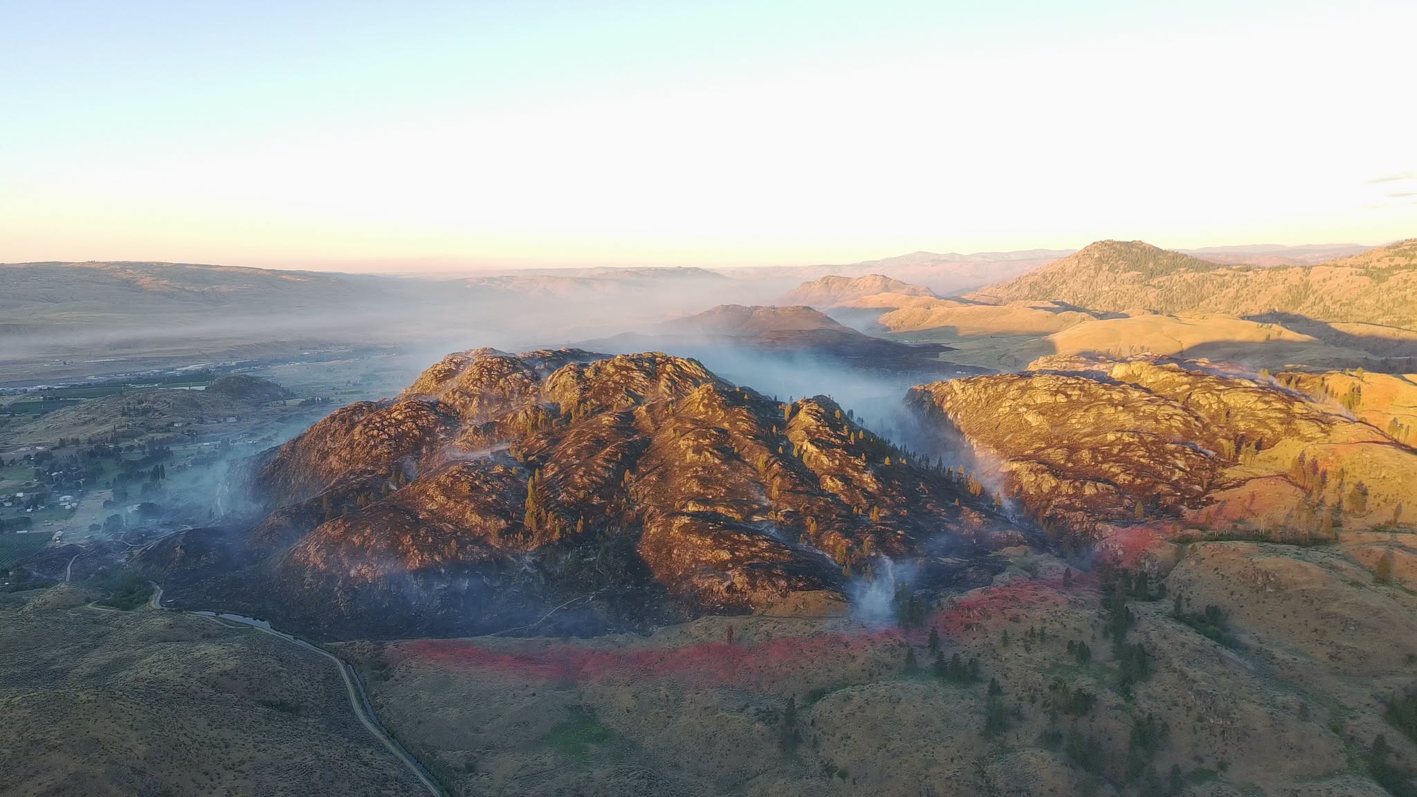 Mountain ridge at sunrise with soft fog filling the valleys and distant hills bathed in warm light