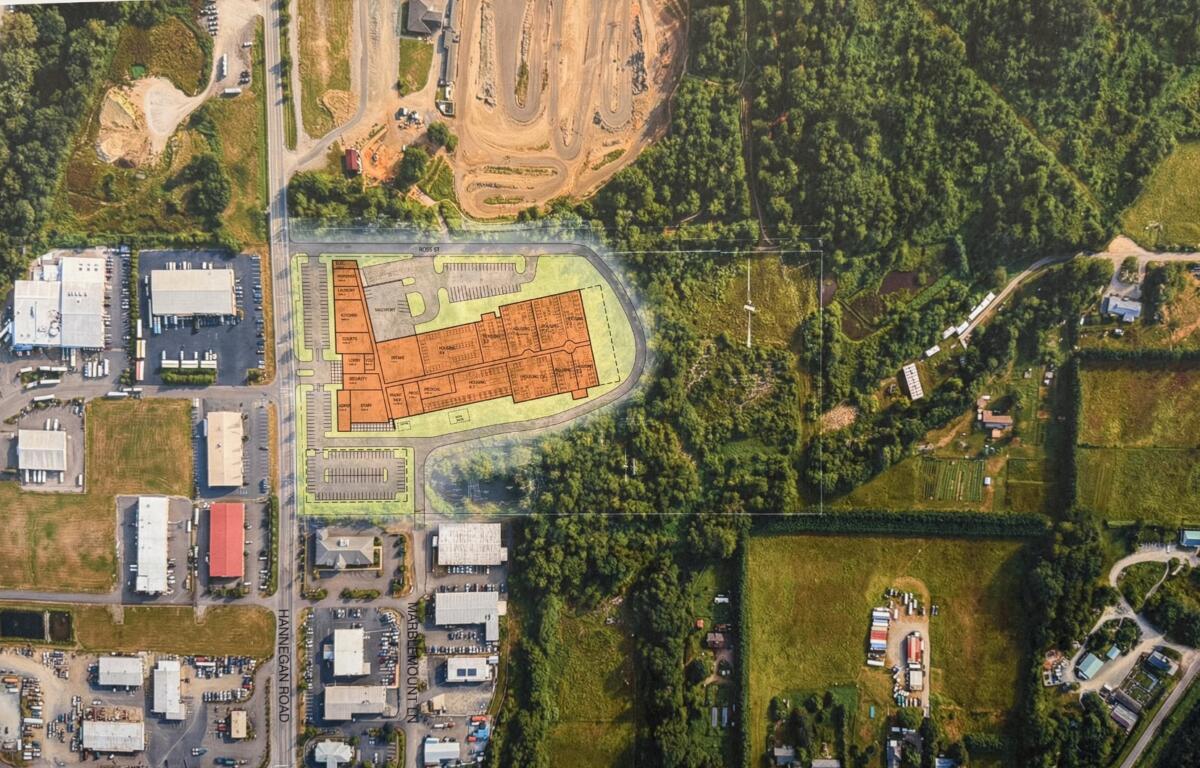 Aerial view of a site plan with an orange building footprint over a mixed industrial and green area; caption reads 'DRAFT - SITE TEST FIT CONTEXT'.