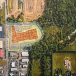 Aerial view of a site plan with an orange building footprint over a mixed industrial and green area; caption reads 'DRAFT - SITE TEST FIT CONTEXT'.