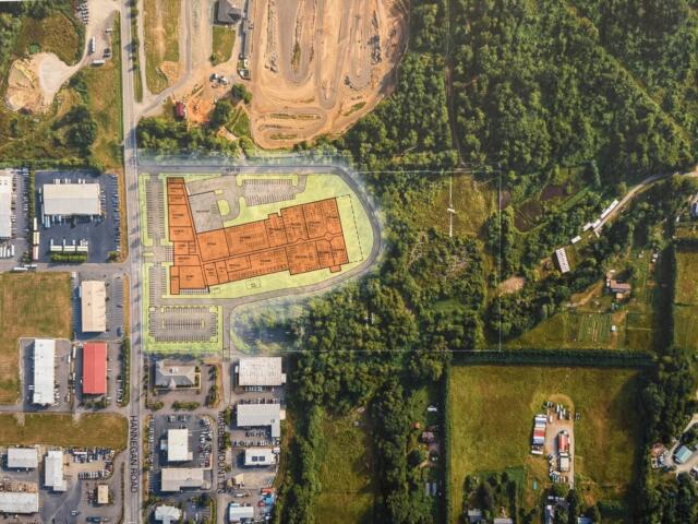 Aerial view of a site plan with an orange building footprint over a mixed industrial and green area; caption reads 'DRAFT - SITE TEST FIT CONTEXT'.