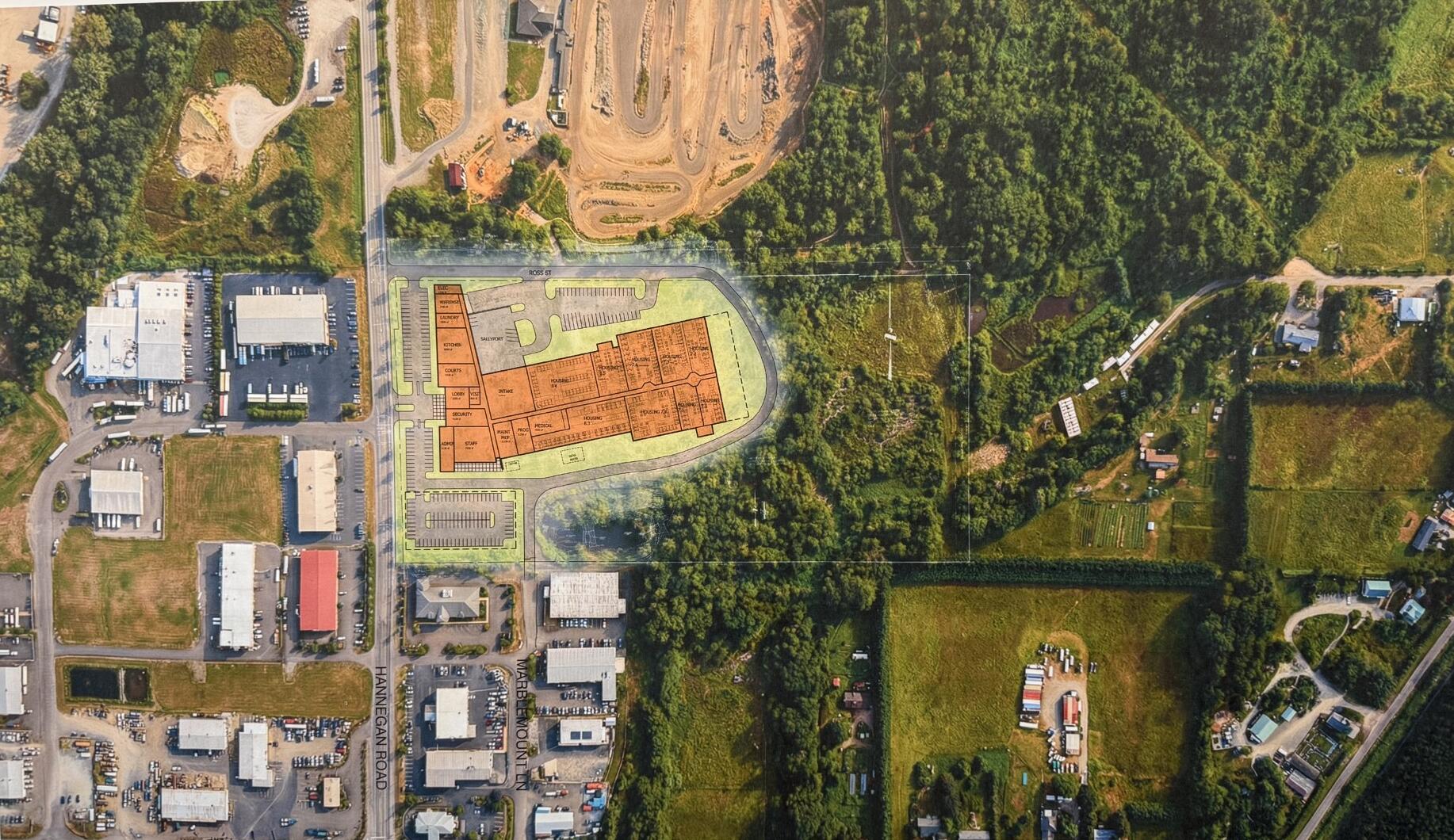 Aerial view of a site plan with an orange building footprint over a mixed industrial and green area; caption reads 'DRAFT - SITE TEST FIT CONTEXT'.